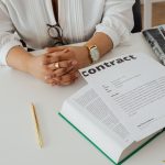 Une personne examine un contrat à un bureau avec des documents et un livre