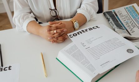 Une personne examine un contrat à un bureau avec des documents et un livre