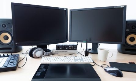 Bureau avec deux moniteurs noirs, ordinateur portable, claviers, souris et enceintes de monitoring