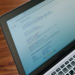 Ordinateur portable affichant du contenu textuel, posé sur un bureau en bois