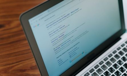 Ordinateur portable affichant du contenu textuel, posé sur un bureau en bois