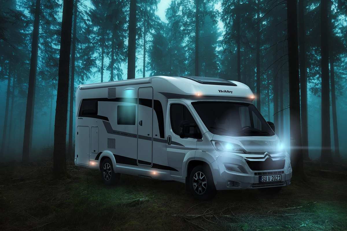 Camion‑moteur blanc, phares allumés, stationné en forêt brumeuse Camion‑moteur blanc, phares allumés, stationné en forêt brumeuse