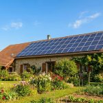 Toit de maison individuelle française avec panneaux solaires photovoltaïques, ciel dégagé, jardin