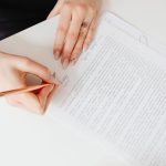 Une main écrit sur un document avec un stylo à une table