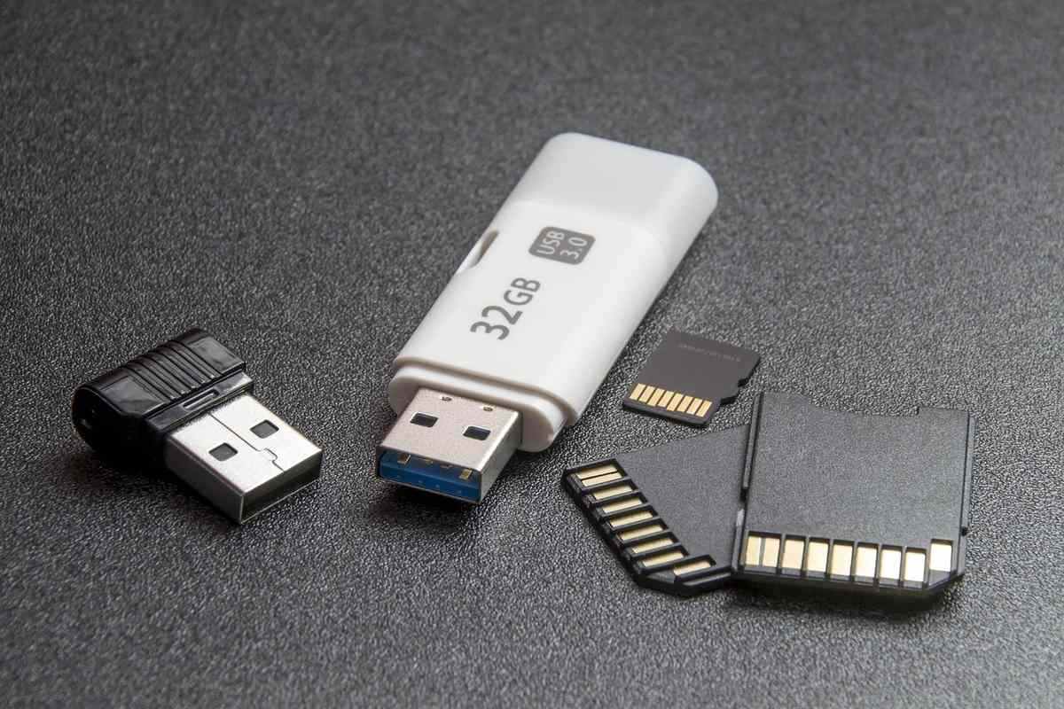 Clé USB blanche et cartes mémoire avec connecteurs dorés sur surface grise