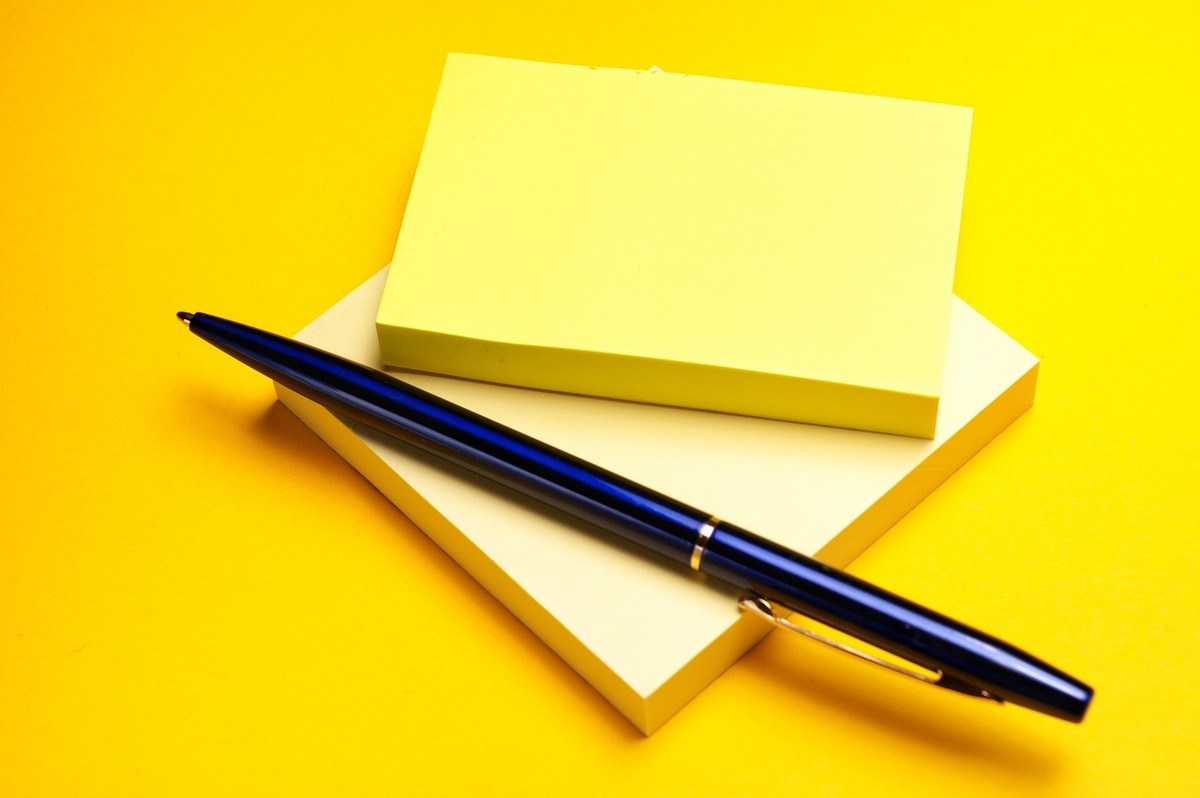 Carnet et stylo bleu sur fond jaune Carnet et stylo bleu sur fond jaune