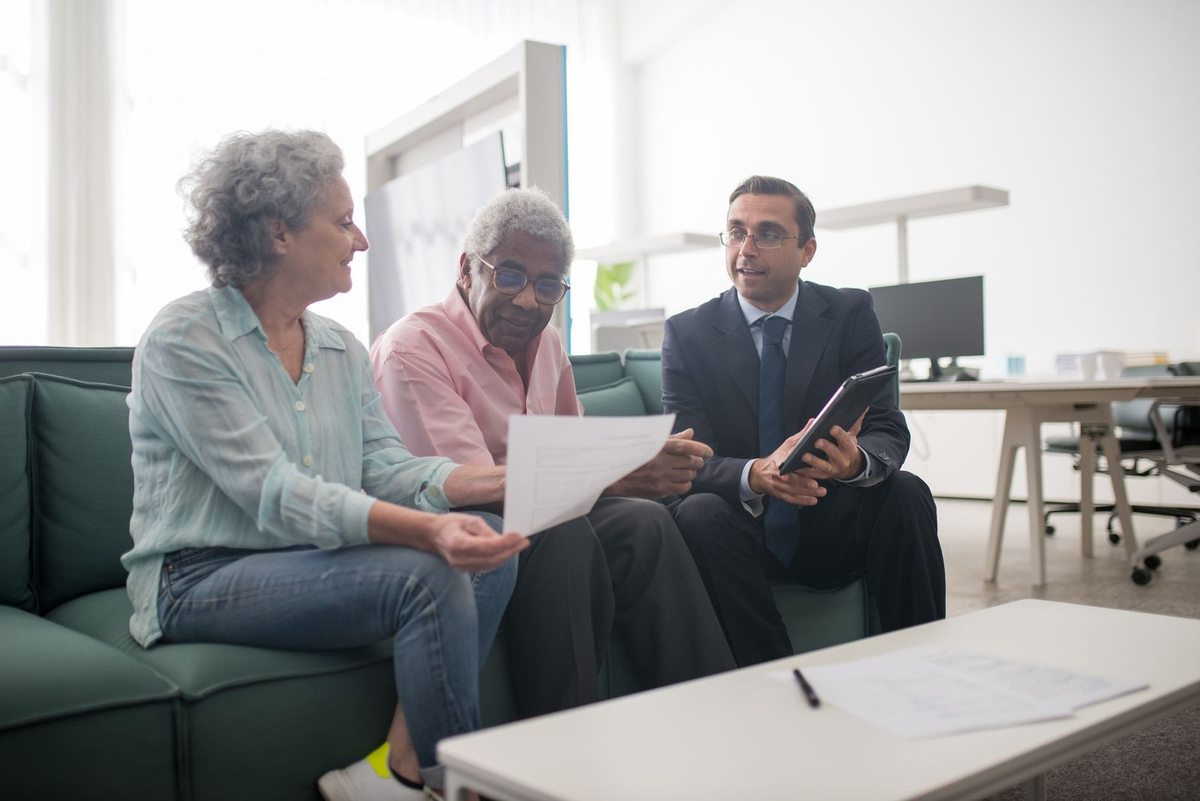 Trois individus en conversation dans un salon, documents et téléphone en main Trois individus en conversation dans un salon, documents et téléphone en main