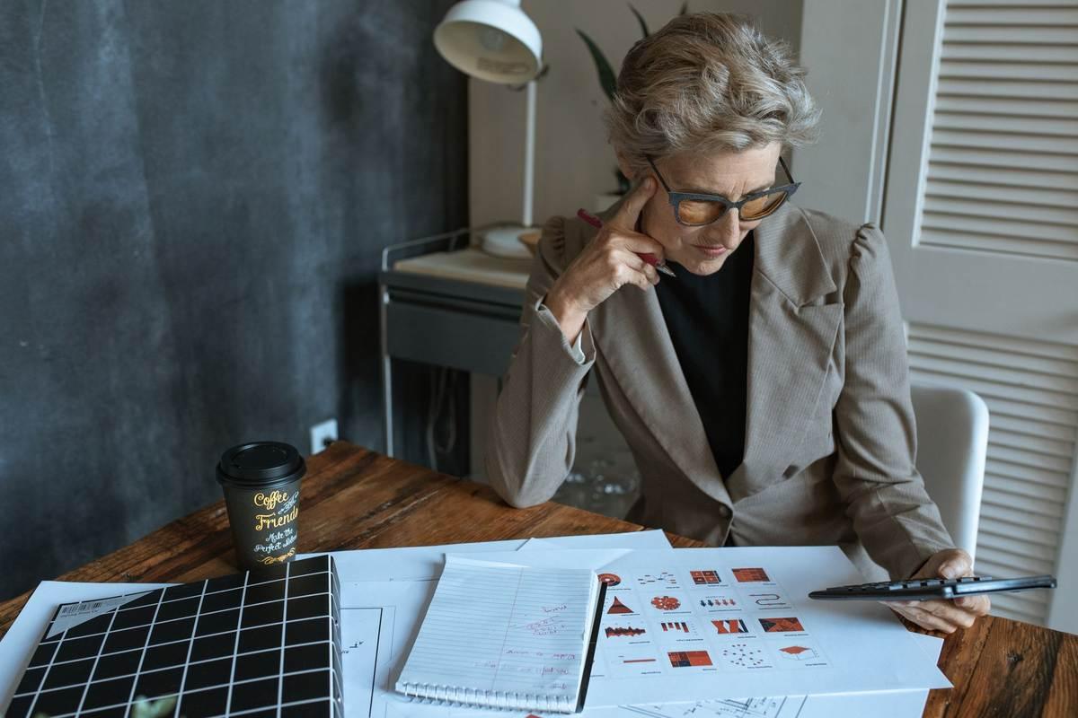 Une femme en costume examine des plans sur un bureau Une femme en costume examine des plans sur un bureau