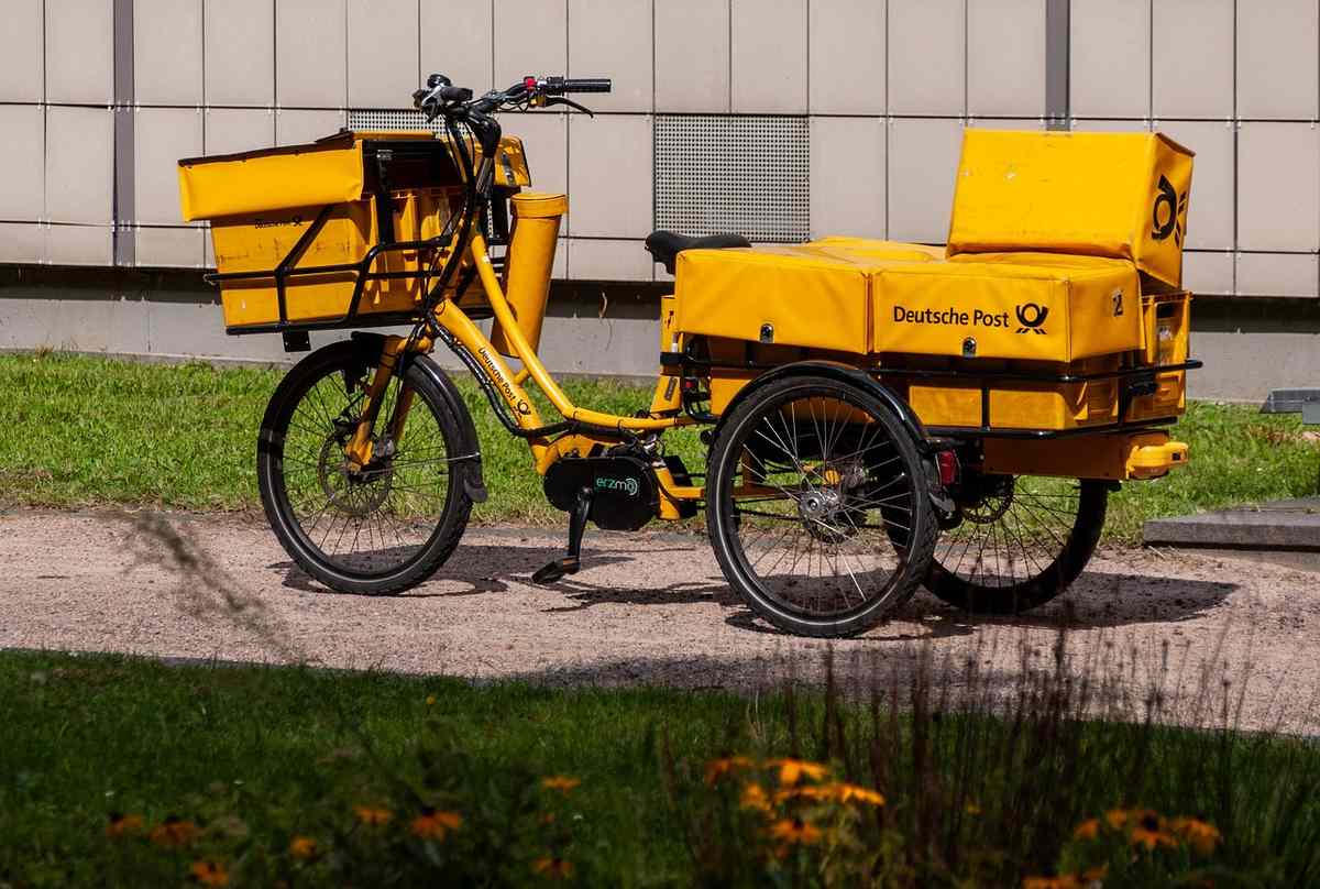 Vélo cargo jaune avec deux caisses jaunes garé sur trottoir