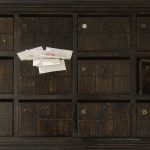 Des enveloppes blanches dépassent d'une boîte aux lettres numérotée