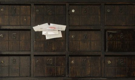 Des enveloppes blanches dépassent d'une boîte aux lettres numérotée