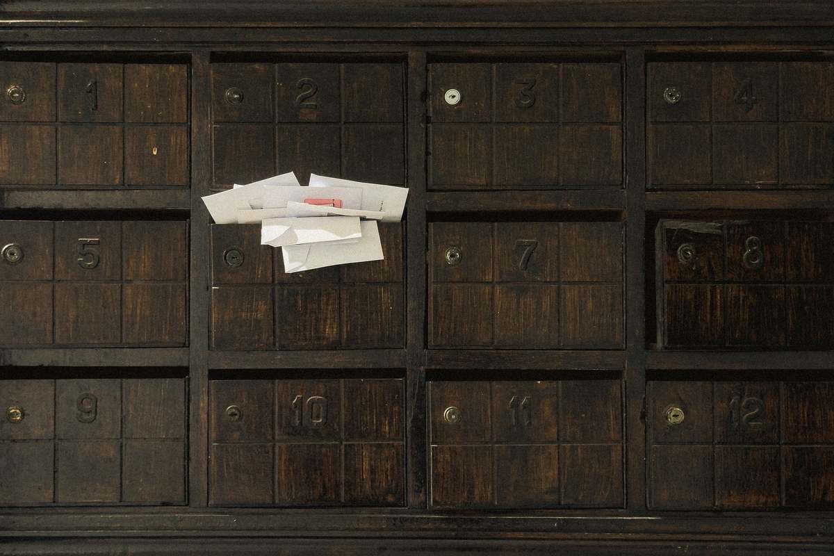 Des enveloppes blanches dépassent d'une boîte aux lettres numérotée