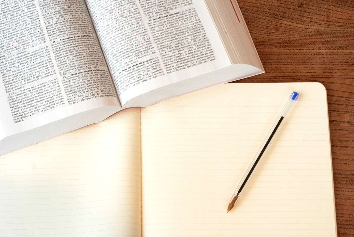 Livre ouvert sur une table, cahier et stylo à côté Livre ouvert sur une table, cahier et stylo à côté