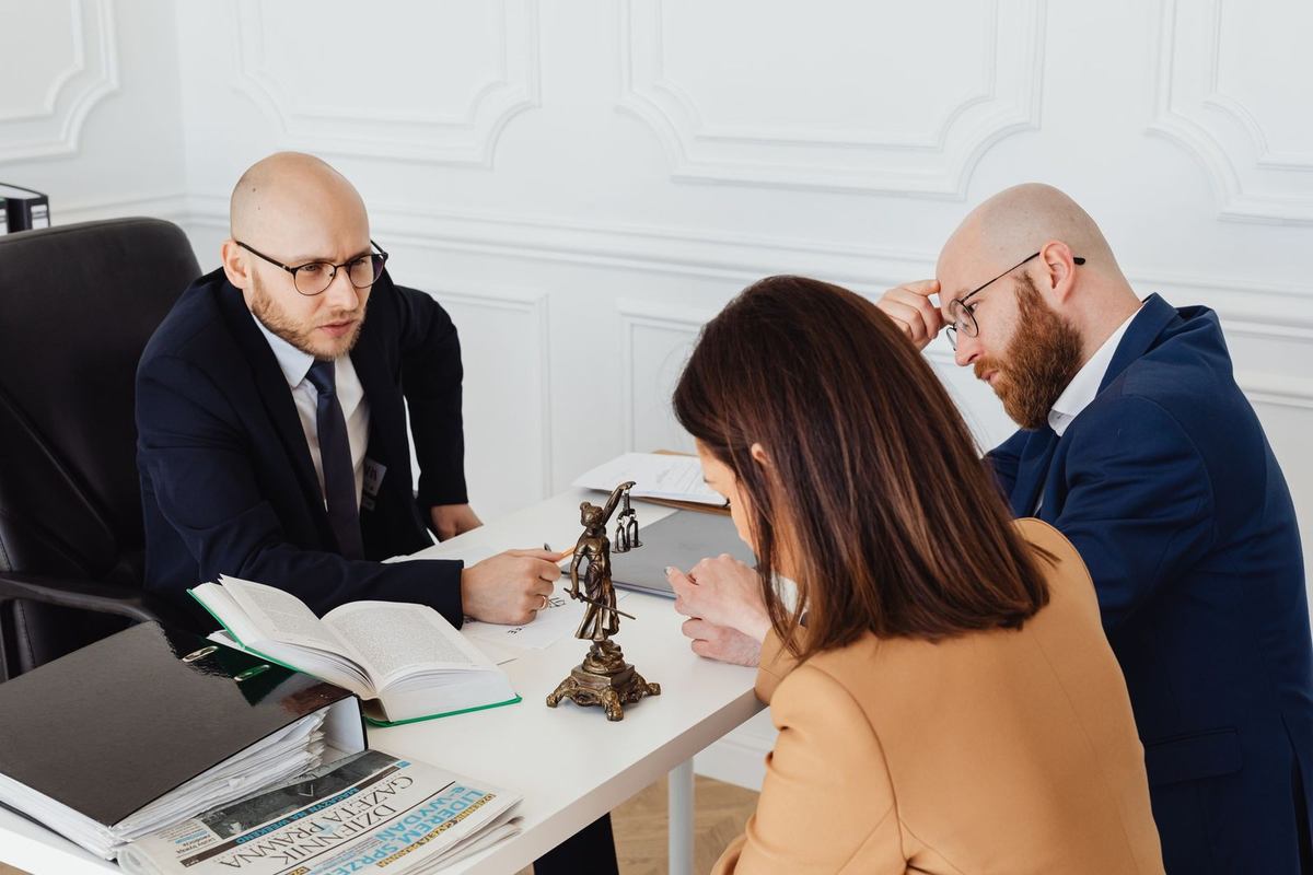 Professionnels discutant autour d'une table avec des documents et une statue de justice Professionnels discutant autour d'une table avec des documents et une statue de justice