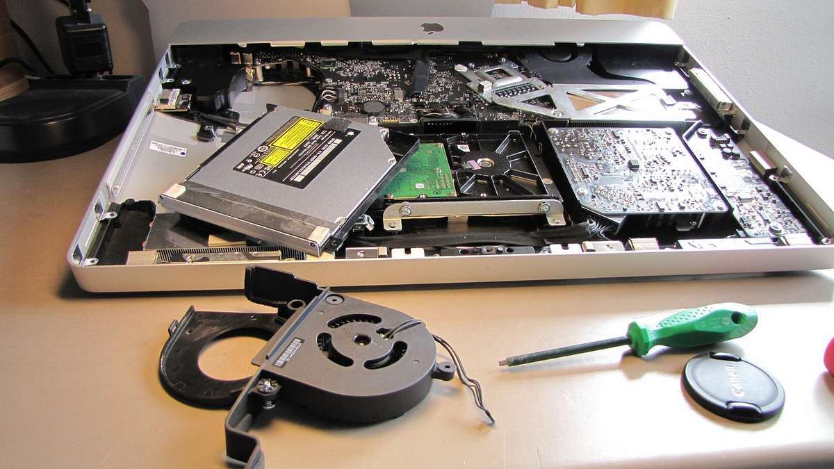 Ordinateur démonté sur une table avec outils et composants électroniques exposés Ordinateur démonté sur une table avec outils et composants électroniques exposés