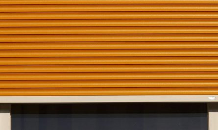 Volet roulant orange partiellement déroulé devant une fenêtre sombre